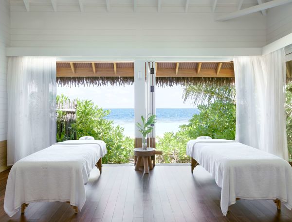 A Room With White Curtains And A Table With A Vase With Flowers