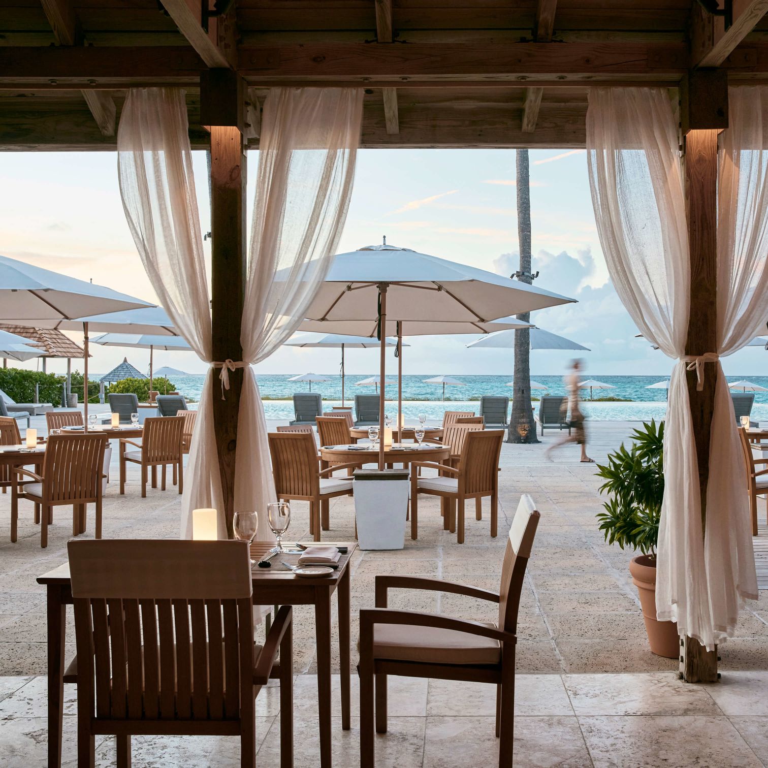 A Patio With Tables And Chairs And Umbrellas