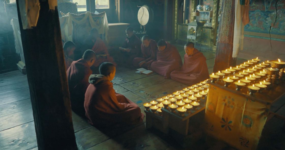 A Group Of People Sitting In A Room With A Table With Food