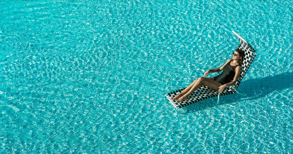 A Person Sitting In A Chair In The Water Holding An Umbrella