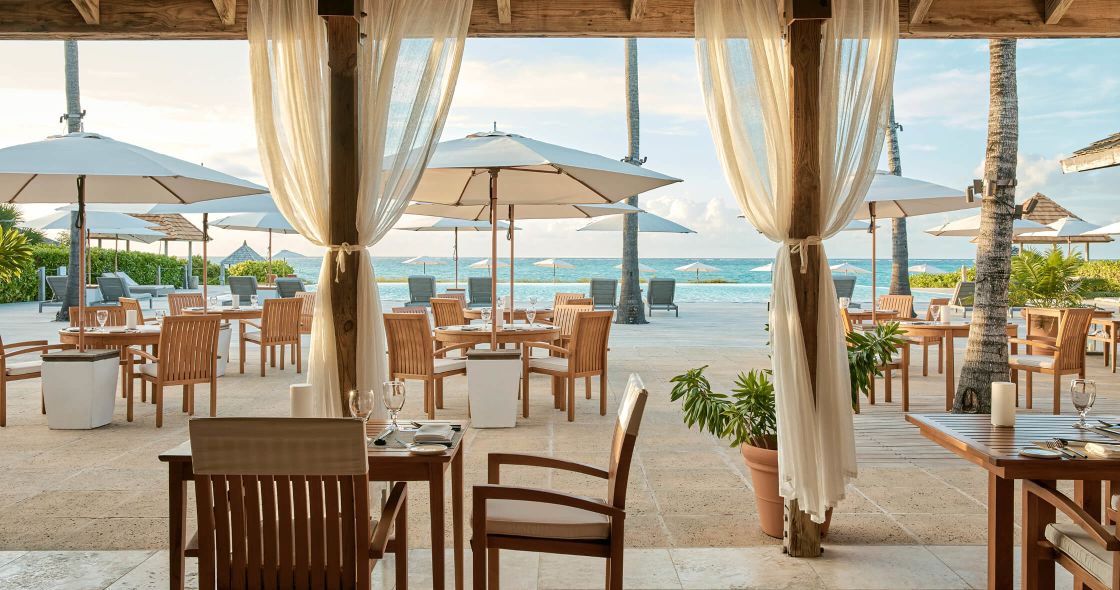 A Patio With Tables And Chairs And Umbrellas