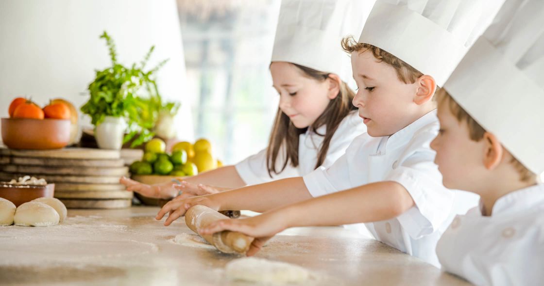 A Couple Of Kids Sitting At A Table With Food