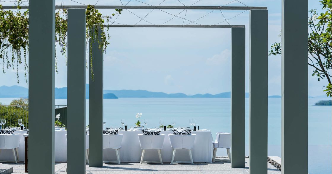 A Patio With Tables And Chairs Overlooking The Ocean