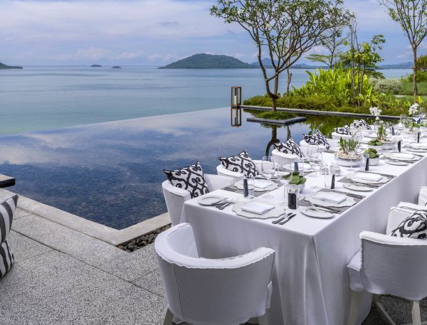 A Table Set With White Chairs And A View Of The Ocean