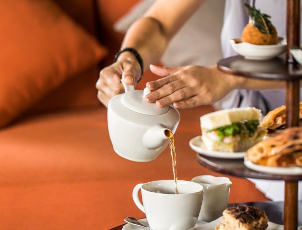 A Person Pouring A Drink Into A Cup