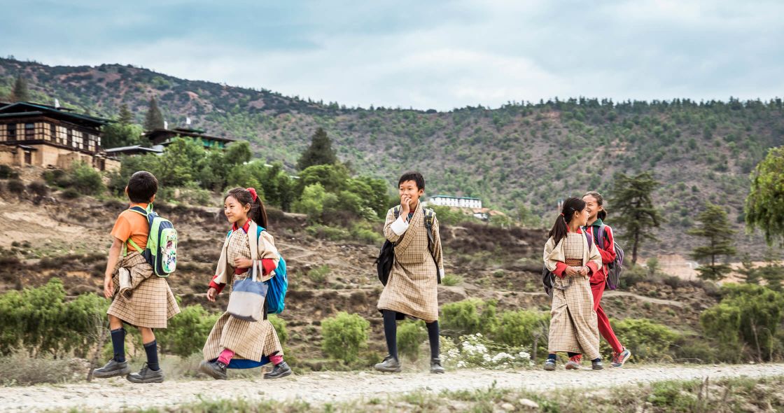 A Group Of People Standing On A Hill With Trees And Buildings In The Background
