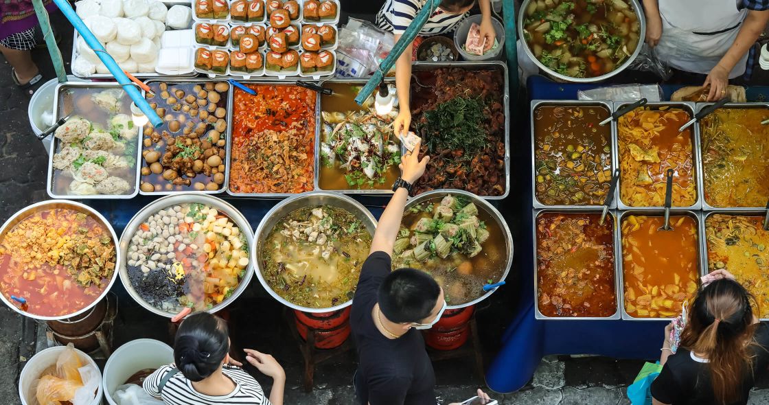 A Group Of People Sitting At A Table Full Of Food