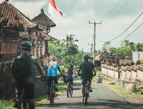 A Group Of People Riding Bikes On A Road Next To A Building