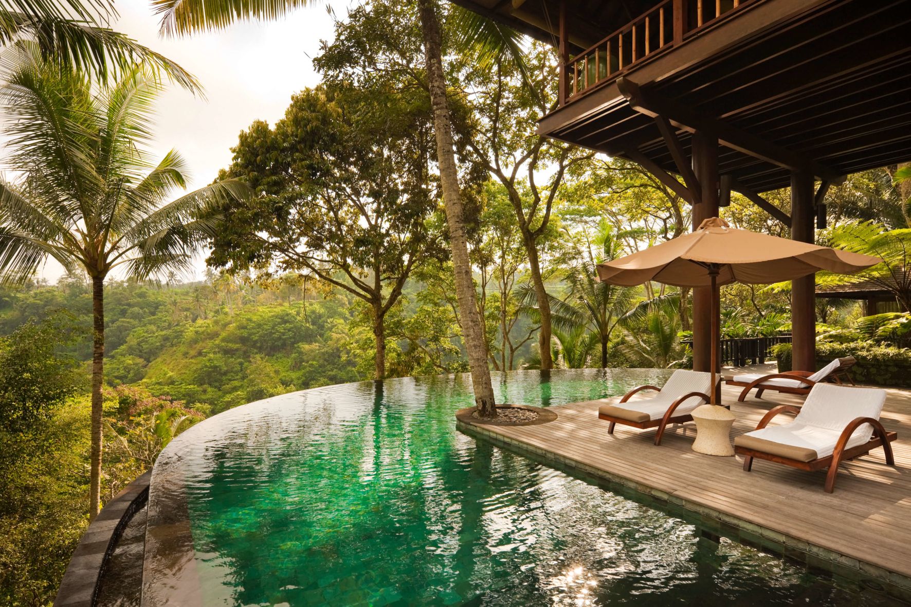 A Pool With Chairs And Umbrellas By A House