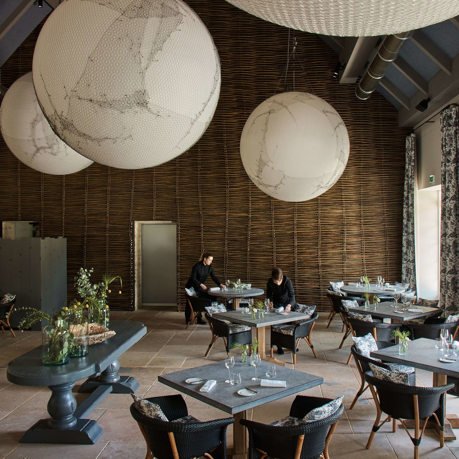 A Couple Of People Sitting At Tables With Large White Balls From The Ceiling