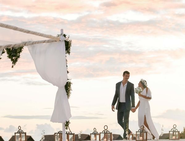 A Bride And Groom Walking Down The Beach